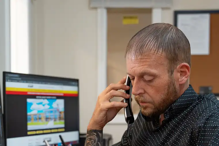 Bail bond agent at desk, talking on phone and reviewing paperwork